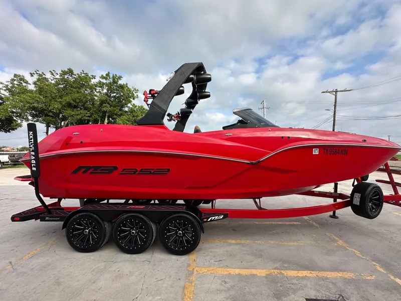Slide: The Image of A red 2023 MB SPORTS B52 boat on a trailer, featuring a distinctive black tower. - 7