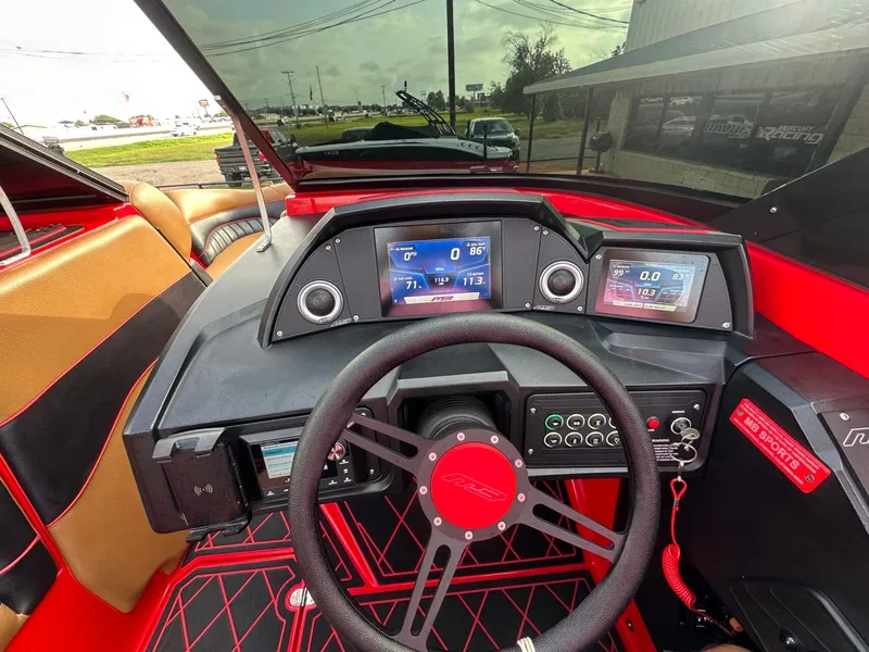 Slide: The Image of The cockpit of a 2023 MB SPORTS B52 boat with modern instruments and a red steering wheel. - 35