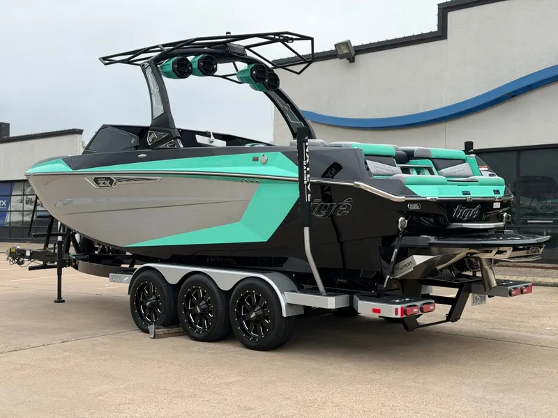 Slide: The Image of The image shows a 2025 Tigé Ultré 23ZX boat with turquoise and gray design on a trailer. - 3