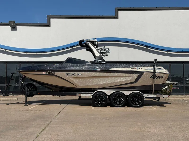 The Image of A 2022 Tigé 25ZX boat on a trailer in front of a building. - 1