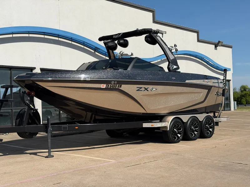 Slide: The Image of A 2022 Tigé 25ZX boat on a trailer in front of a modern building. - 2