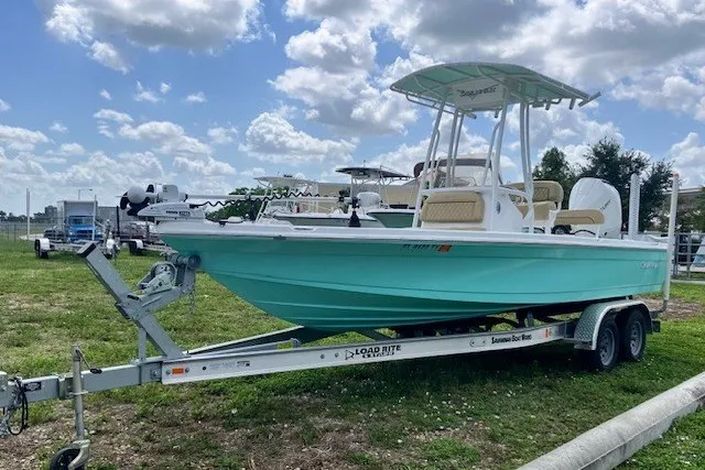 Slide: The Image of 2025 Savannah 220 IS boat on trailer, parked outdoors under a cloudy sky. - 0