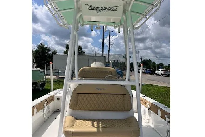 Slide: The Image of 2025 Savannah 220 IS boat with tan seating and white frame under cloudy sky. - 3