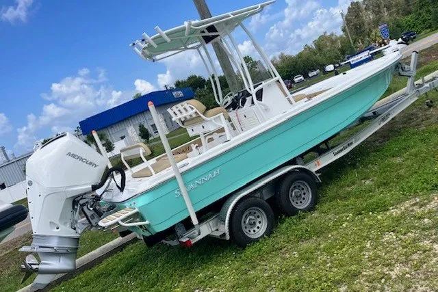 Slide: The Image of 2025 Savannah 220 IS boat on trailer with Mercury outboard, parked outdoors. - 1