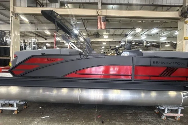 Slide: The Image of 2027 Bennington 22 M Open Fastback Quad Bench pontoon boat in a factory setting. - 1