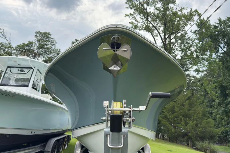 Slide: The Image of 2019 Sea Hunt Gamefish 27 boat on trailer, surrounded by trees and cloudy sky. - 3