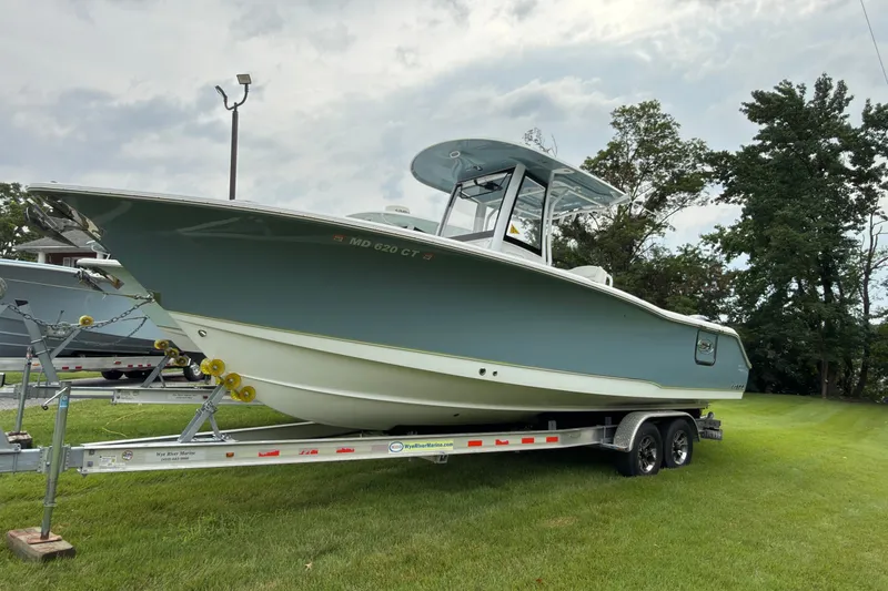 The Image of 2019 Sea Hunt Gamefish 27 boat on trailer, parked on grass under cloudy sky. - 0