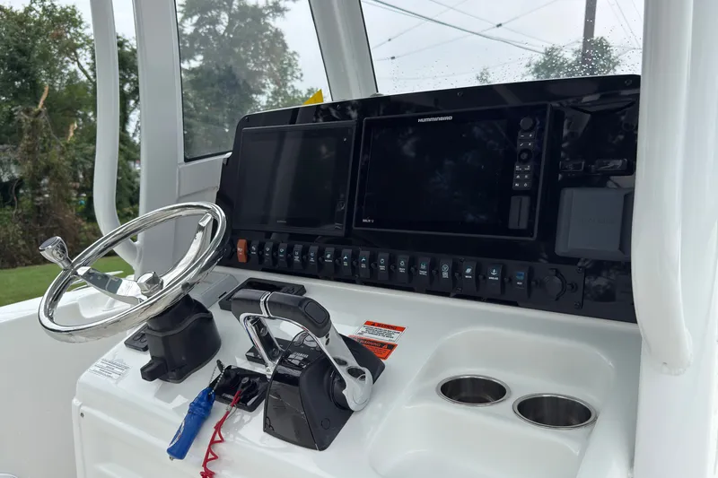Slide: The Image of 2019 Sea Hunt Gamefish 27 helm with steering wheel, controls, and navigation display. - 19