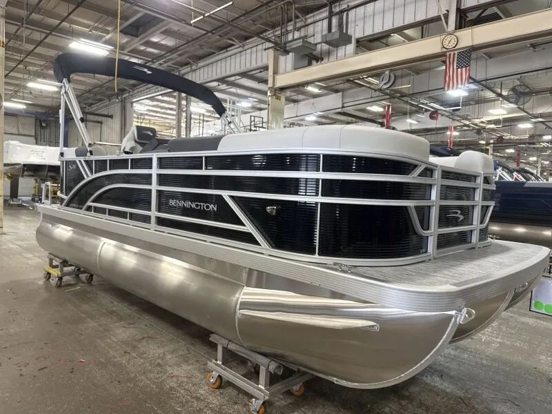 The Image of Bennington 20 S1 STERN RADIUS 2027 in a warehouse, featuring an aluminum hull and black railing. - 1