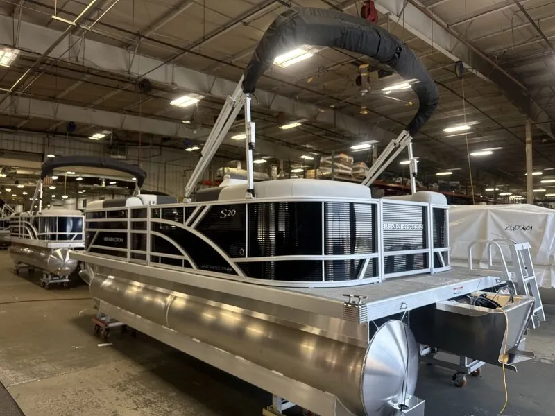 The Image of A Bennington 20 S1 STERN RADIUS pontoon boat is in a warehouse. It features sleek black and silver accents. - 1