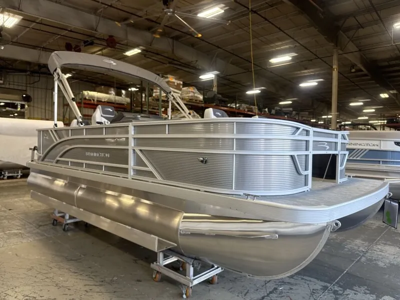 The Image of A Bennington pontoon boat is in a warehouse. It features a modern design and silver color. - 1