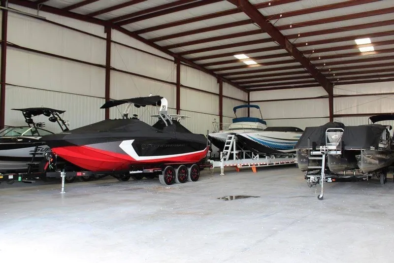 Slide: The Image of Several boats in a large storage facility, including a red and black boat on a trailer. - 9