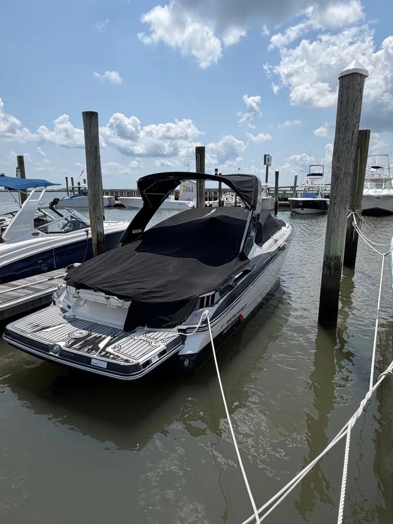The Image of A 2013 Monterey 288SS Super Sport is docked in the water, covered with a black tarp. - 0