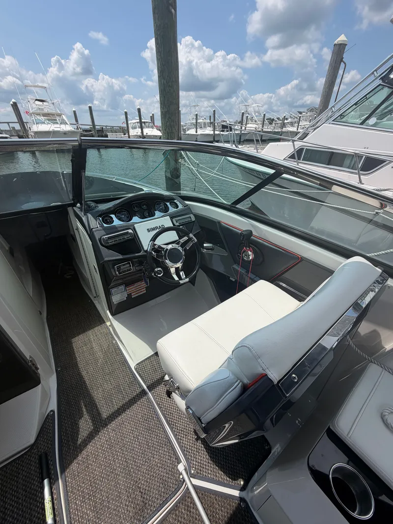 Slide: The Image of The image shows the cockpit of a 2013 Monterey 288SS Super Sport. It features a modern dashboard with a sleek steering wheel and comfortable seating. Other boats and a cloudy sky are visible in the background. - 11