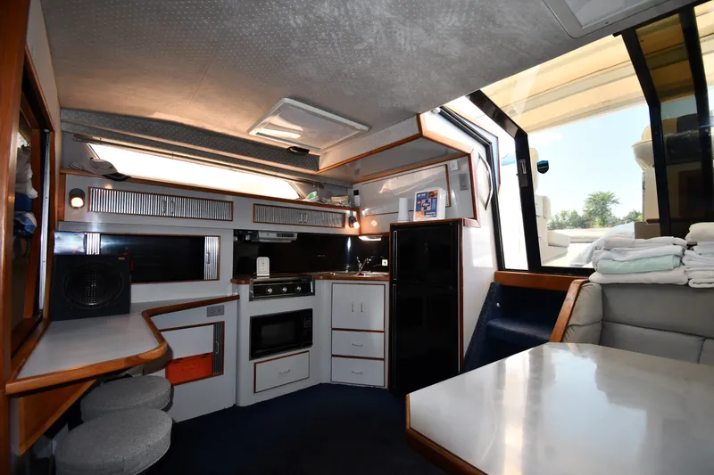 Slide: The Image of Interior of 1989 Sea Ray 390 Express Cruiser with kitchen and seating area. - 30
