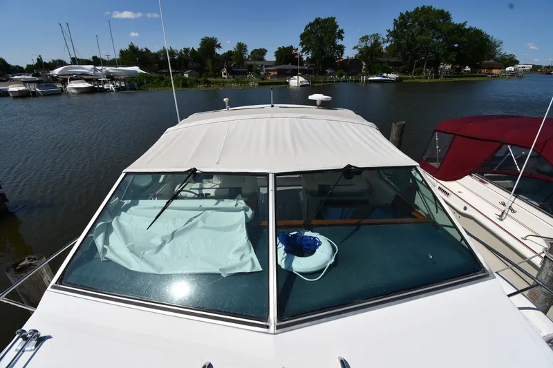 Slide: The Image of 1989 Sea Ray 390 Express Cruiser docked at marina, featuring covered windshield and calm waters. - 7
