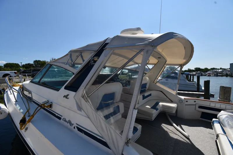 Slide: The Image of 1989 Sea Ray 390 Express Cruiser docked, featuring spacious seating and clear canopy. - 4