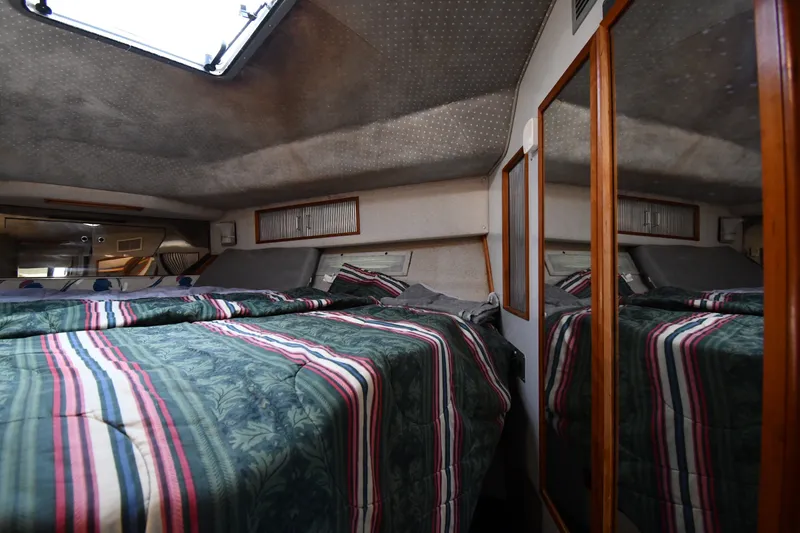 Slide: The Image of Interior cabin of 1989 Sea Ray 390 Express Cruiser with striped bedding and mirrored closet. - 23