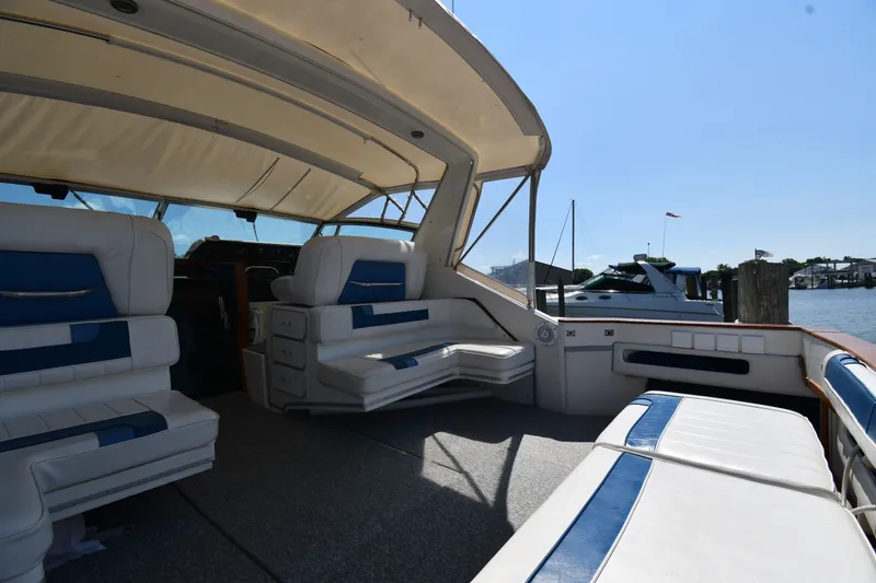 Slide: The Image of 1989 Sea Ray 390 Express Cruiser interior with white and blue seating, docked at marina. - 16