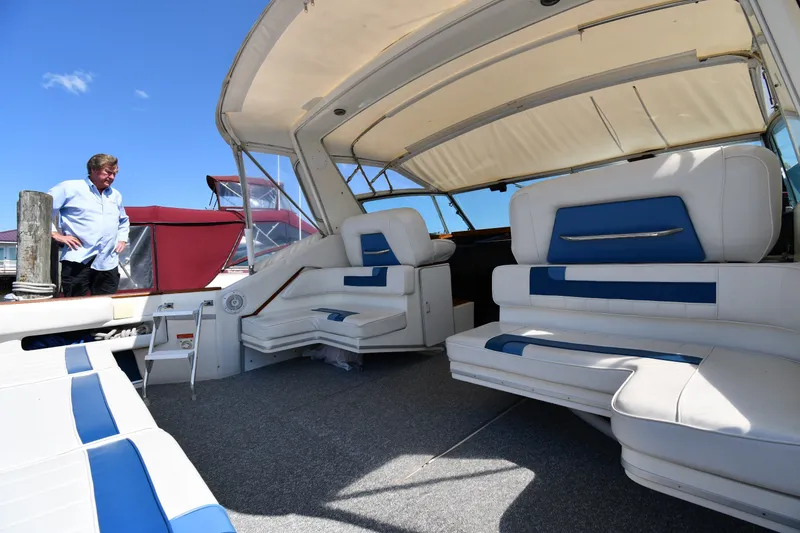 Slide: The Image of 1989 Sea Ray 390 Express Cruiser interior with white and blue seating, docked under clear sky. - 17