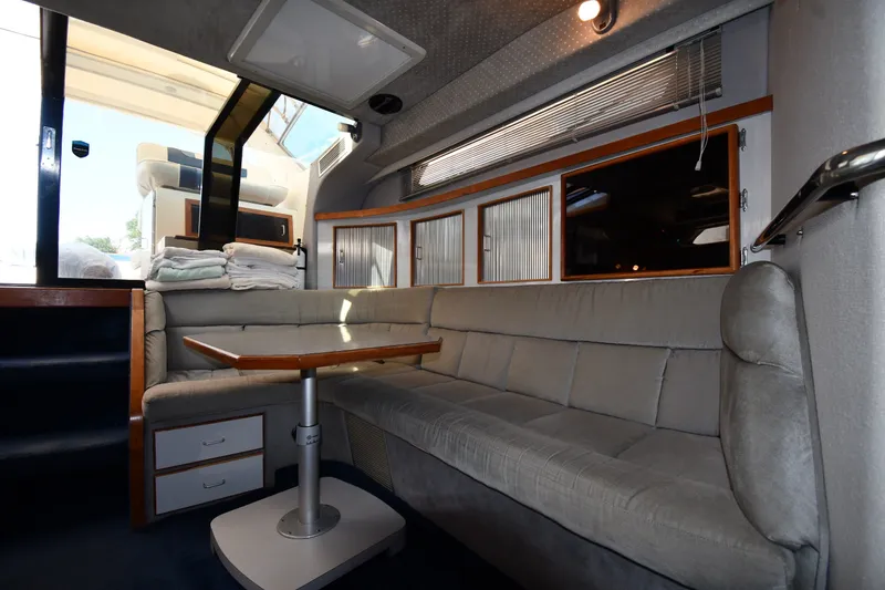 Slide: The Image of Interior of 1989 Sea Ray 390 Express Cruiser with plush seating and wooden table. - 29