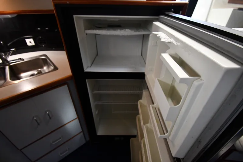 Slide: The Image of 1989 Sea Ray 390 Express Cruiser kitchen with open refrigerator and stainless steel sink. - 37