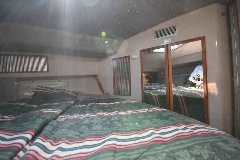 Slide: The Image of Interior cabin of 1989 Sea Ray 390 Express Cruiser with striped bedding and mirrored closet. - 26