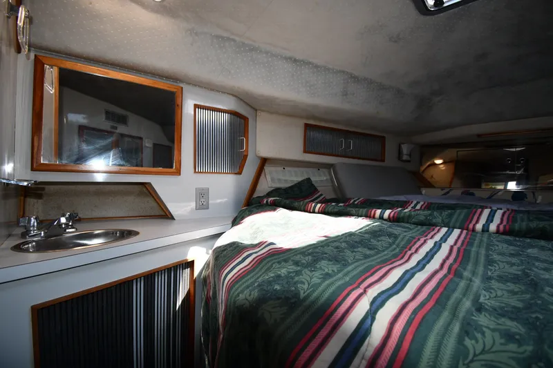 Slide: The Image of 1989 Sea Ray 390 Express Cruiser cabin interior with bed, sink, and storage. - 24