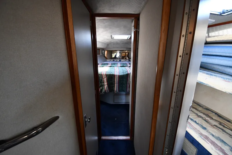 Slide: The Image of Interior view of 1989 Sea Ray 390 Express Cruiser cabin with bed and striped bedding. - 21