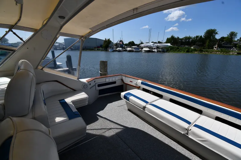 Slide: The Image of 1989 Sea Ray 390 Express Cruiser interior with waterfront view, featuring white seating and blue accents. - 19