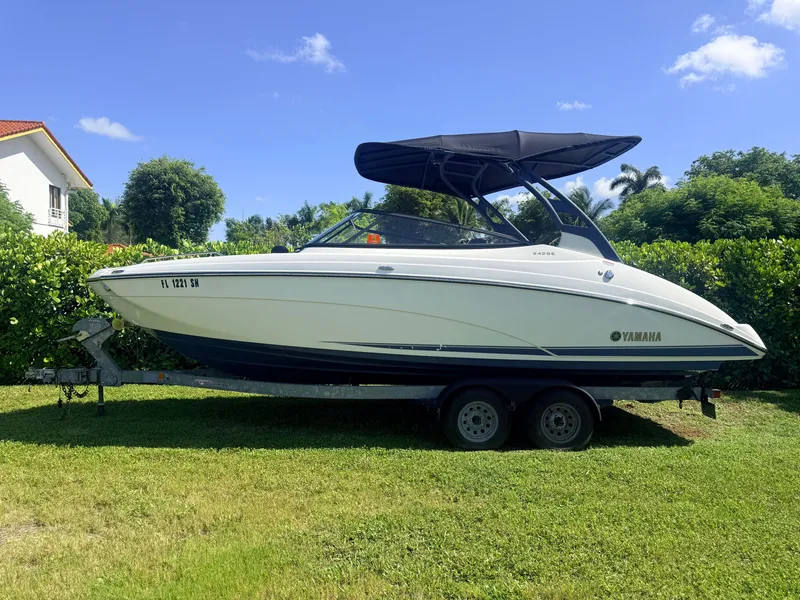 Slide: The Image of A 2020 Yamaha 242SE boat on a trailer, set on a grassy lawn. - 1