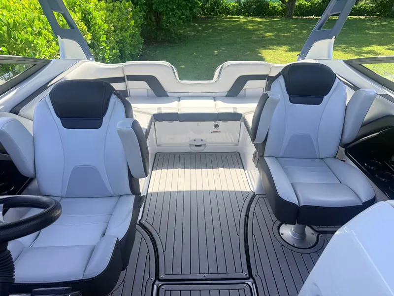 Slide: The Image of Interior of a 2020 Yamaha Boats 242SE with gray and black seating, surrounded by lush greenery. - 6