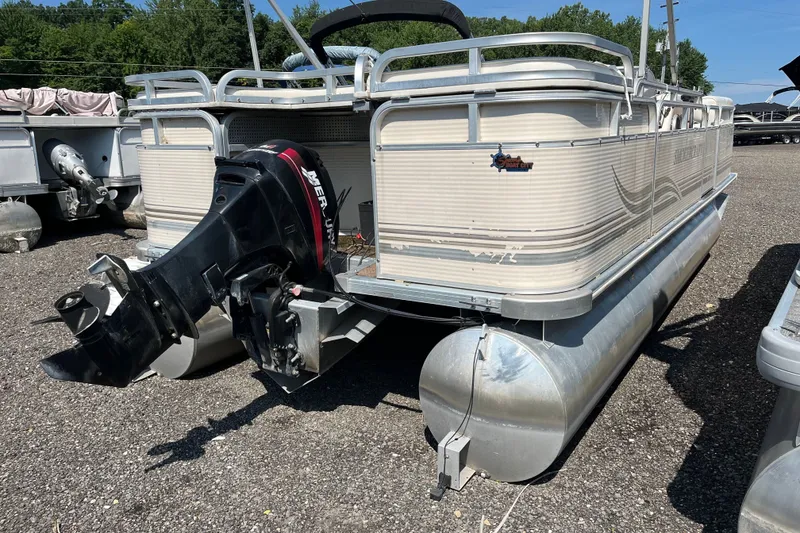 Slide: The Image of 2001 SMOKERCRAFT pontoon boat with outboard motor, parked on gravel lot. - 2