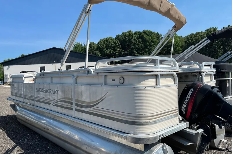 Slide: The Image of 2001 SMOKERCRAFT pontoon boat with Mercury outboard motor, parked outdoors. - 3