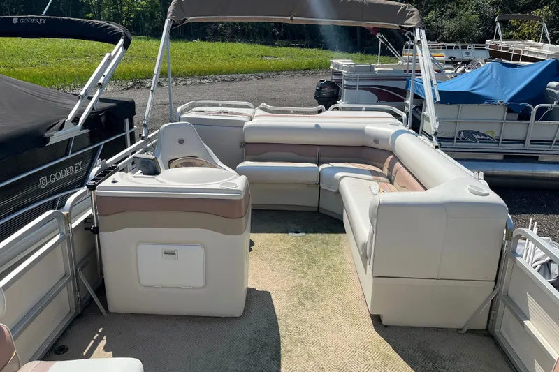 Slide: The Image of 2001 SMOKERCRAFT pontoon boat interior with beige seating and canopy, docked outdoors. - 4