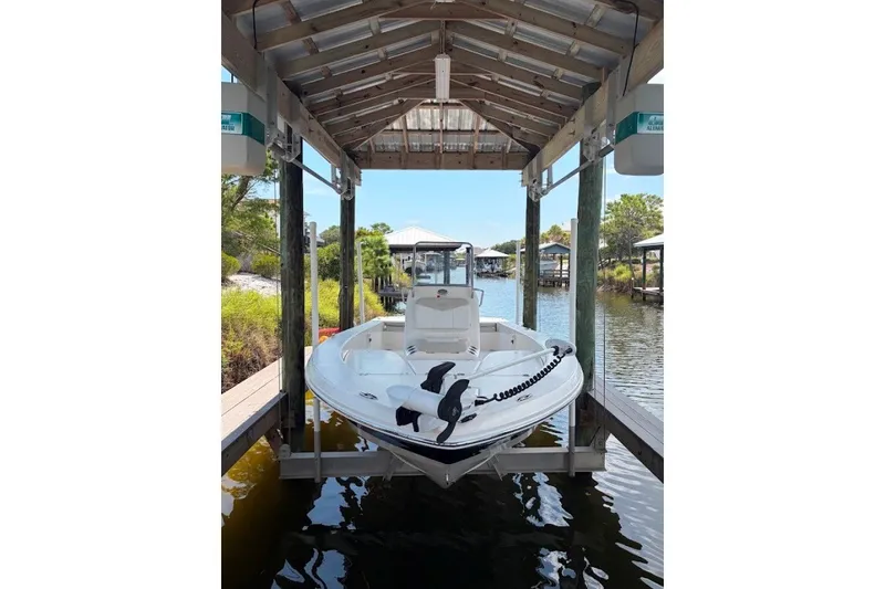 The Image of 2014 Robalo 206 Cayman boat docked under a wooden shelter by the water. - 4