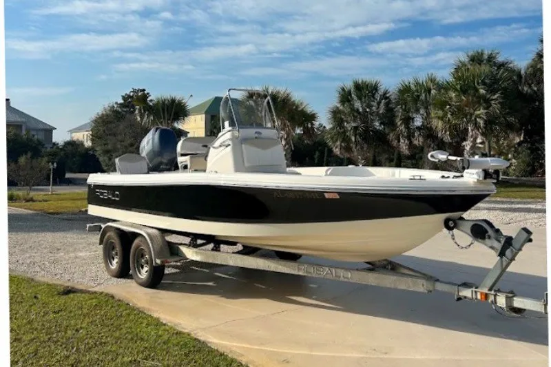 Slide: The Image of 2014 Robalo 206 Cayman boat on trailer, parked outdoors with palm trees in background. - 1