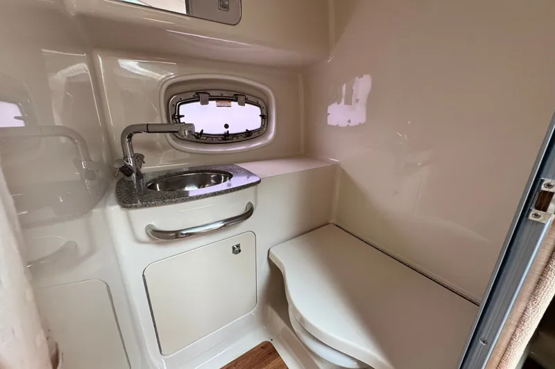 Slide: The Image of 2015 Chaparral 310 Signature boat bathroom with sink, faucet, and porthole window. - 24