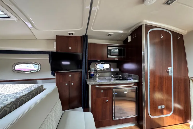 Slide: The Image of 2015 Chaparral 310 Signature yacht interior with kitchenette, TV, and seating area. - 18