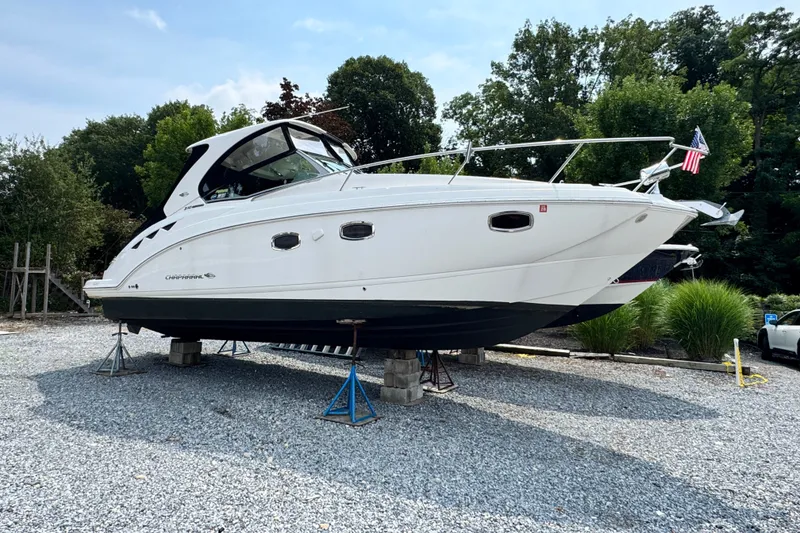 Slide: The Image of 2015 Chaparral 310 Signature boat on stands, surrounded by trees and gravel. - 2