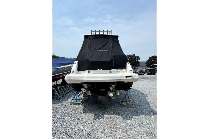 Slide: The Image of 2015 Chaparral 310 Signature boat, rear view, covered, on gravel lot. - 3