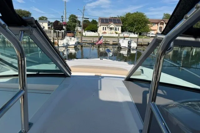 Slide: The Image of 2015 Chaparral 310 Signature boat docked, view from deck, with marina and houses in background. - 35