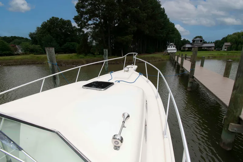 Slide: The Image of 2001 Mainship Pilot 30 docked by a wooden pier in a serene, tree-lined waterway. - 14