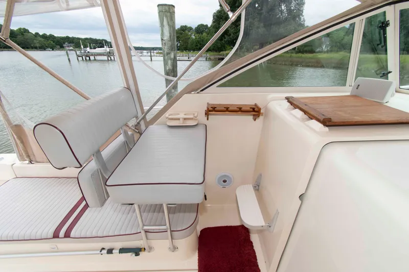 Slide: The Image of 2001 Mainship Pilot 30 boat interior with seating and table, docked by a serene lake. - 8