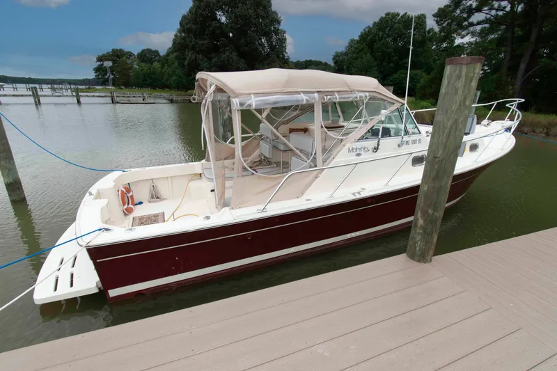 Slide: The Image of 2001 Mainship Pilot 30 docked on calm water, featuring a sleek design and canopy. - 2