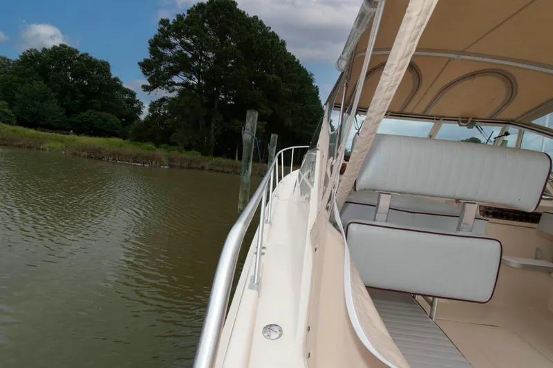 Slide: The Image of 2001 Mainship Pilot 30 boat docked by a serene, tree-lined riverbank. - 15