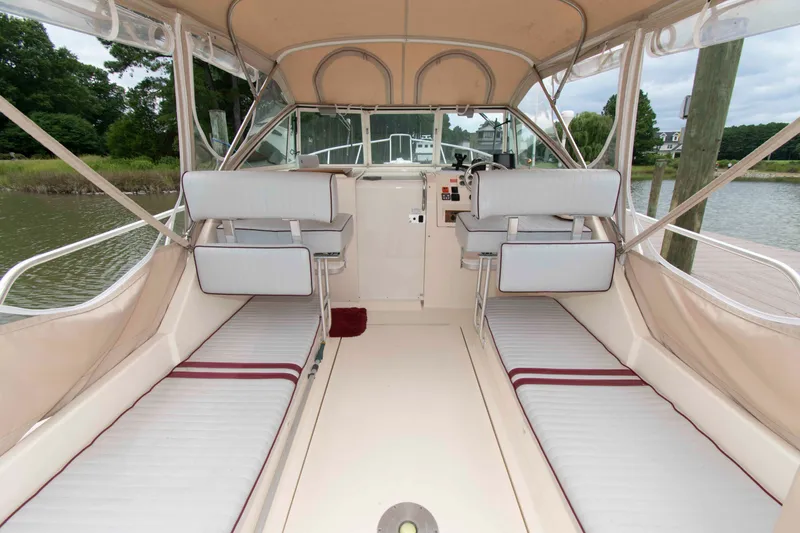 Slide: The Image of 2001 Mainship Pilot 30 interior with seating and helm, docked by a serene waterfront. - 4