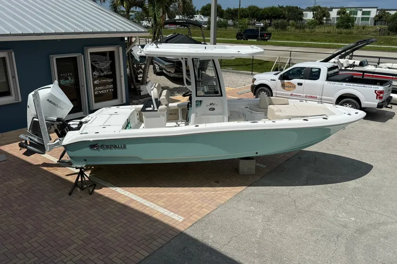 Slide: The Image of 2027 Crevalle 24 HCO boat displayed outdoors near a marine dealership. - 2