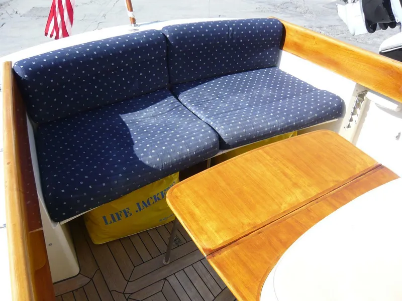 Slide: The Image of Hinckley 36 Classic 1998 boat interior with blue cushioned seating and wooden table. - 25