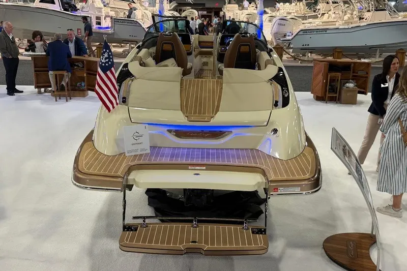 Slide: The Image of 2026 Chris-Craft Launch 27 boat displayed at a boat show with American flag. - 2